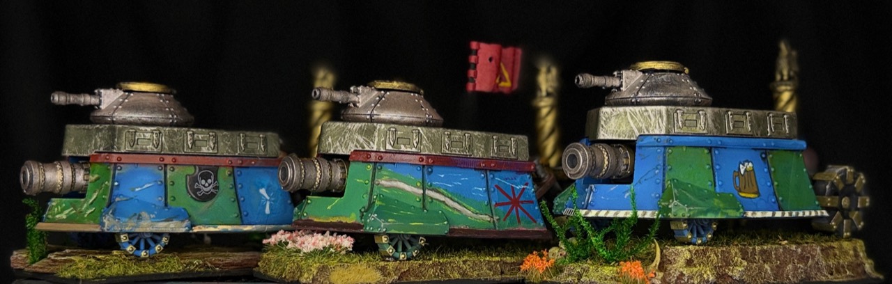 Three individually marked painted fantasy armored vehicles on scenic bases against black.
