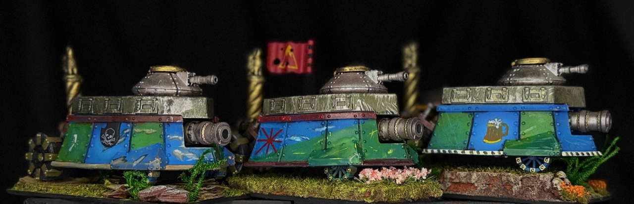 Opposite view of the same three painted armored vehicles, showing their alternate sides and scenic bases.